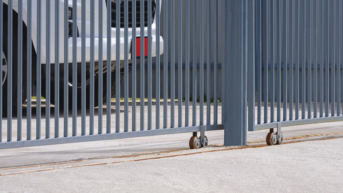 Perspective side view of sliding steel fence gate with white car